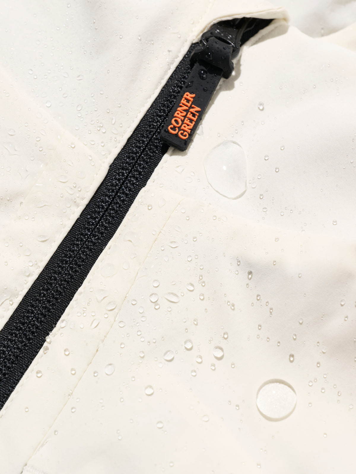 DRIVE Cream golf wind jacket: water droplets beading on the crinkle-textured shell